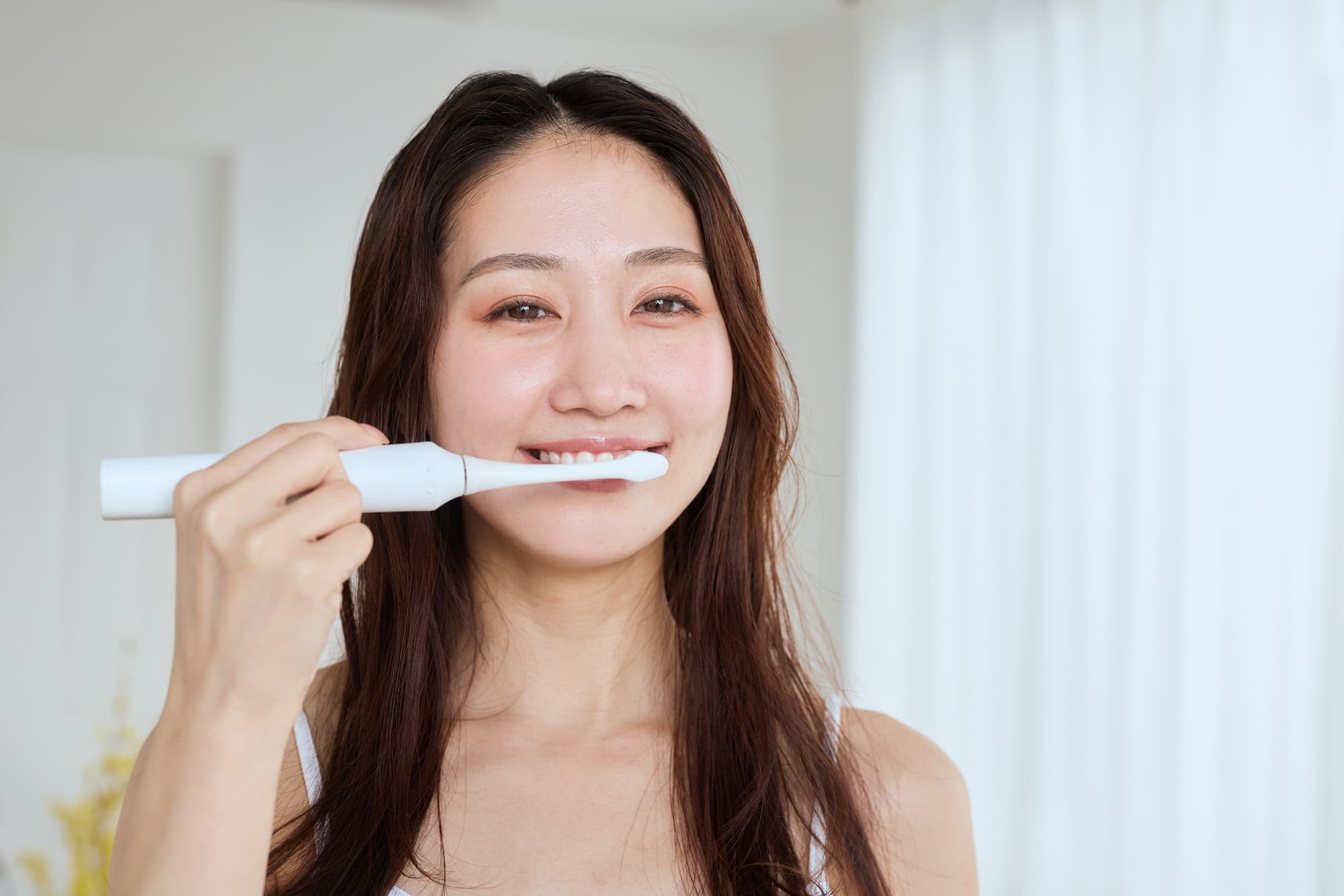電動歯ブラシで歯を磨く女性