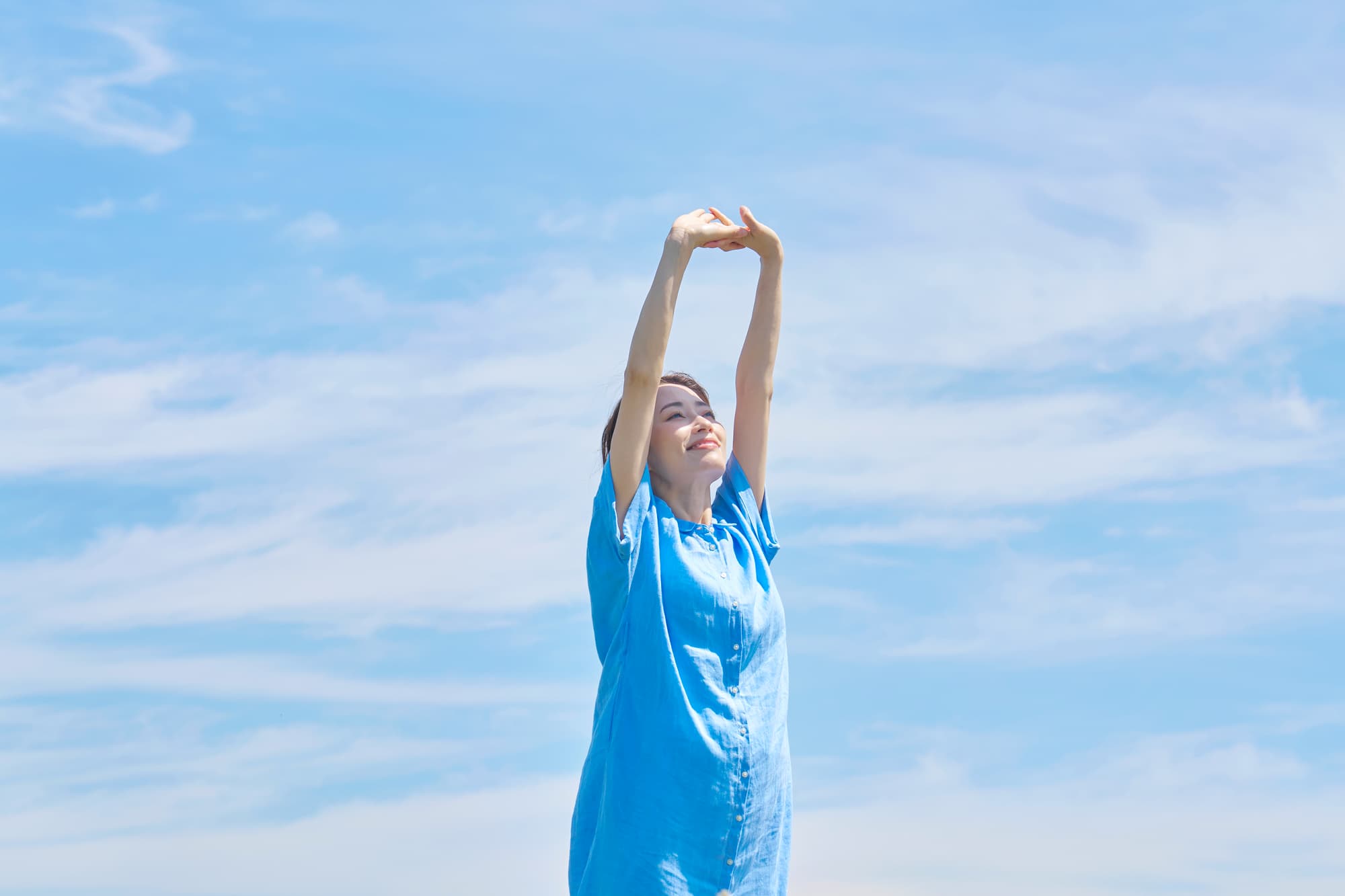 青空の下、背伸びをする女性