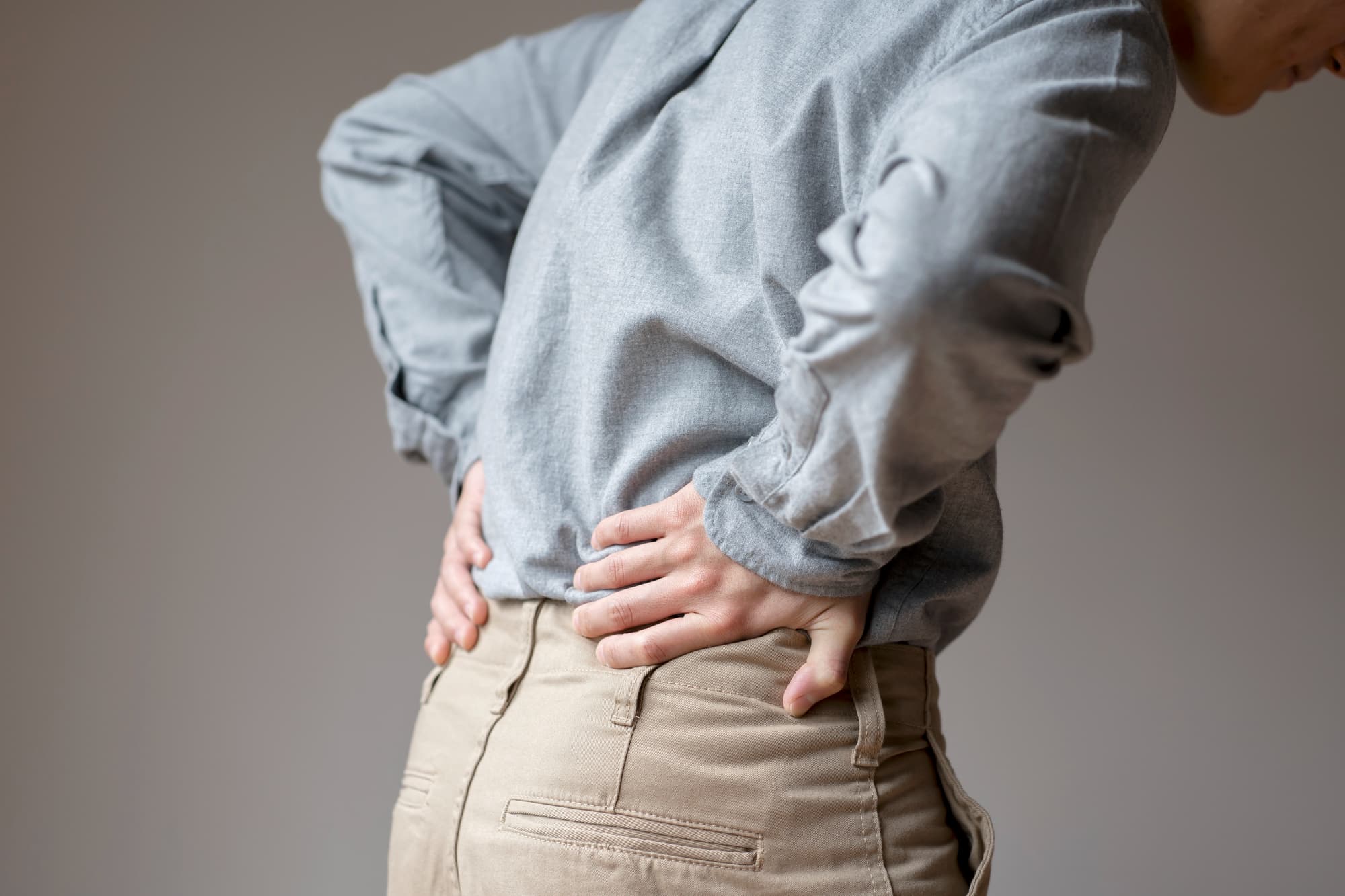 腰を痛がる男性の後ろ姿