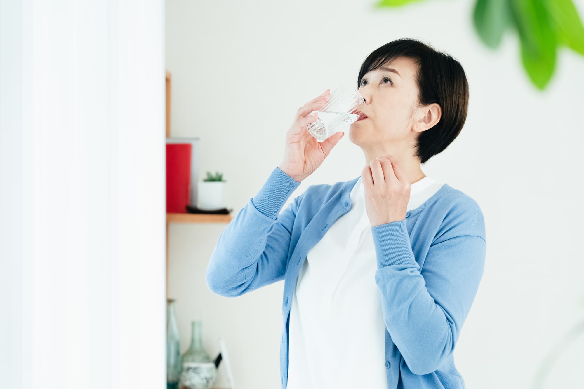 のどが渇いて水を飲む女性