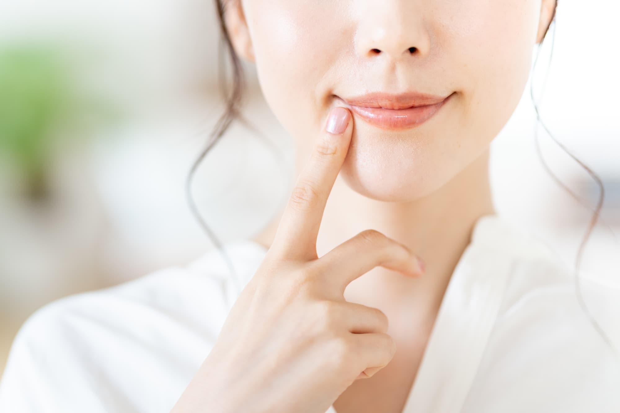 口元を指さす女性