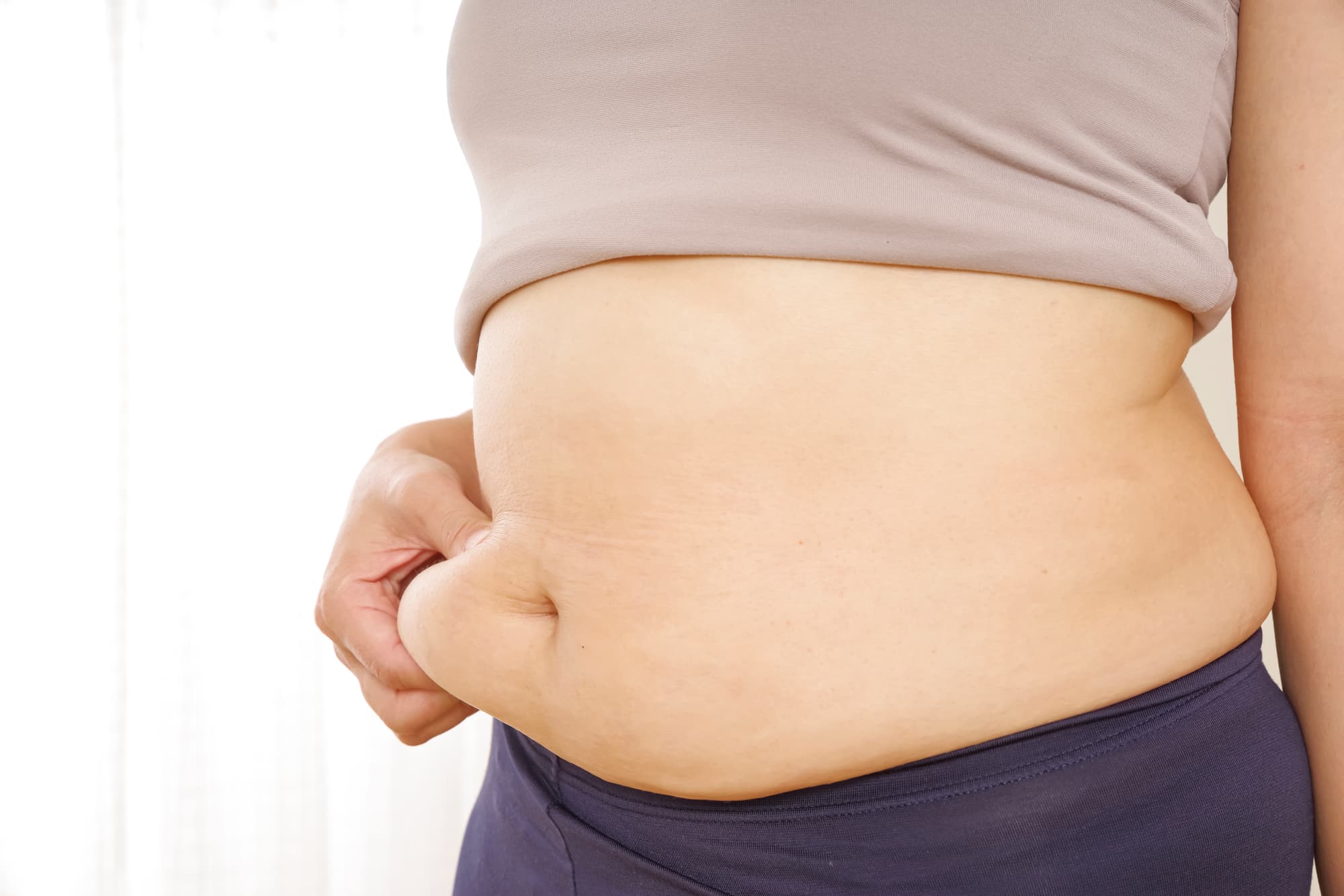ぽっちゃりしたお腹をつまむ女性
