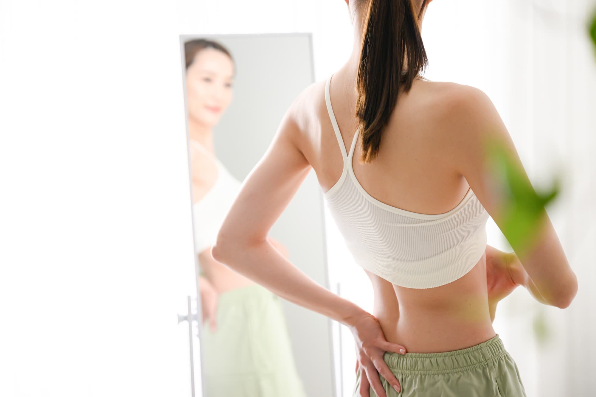 体形を鏡で確認する女性