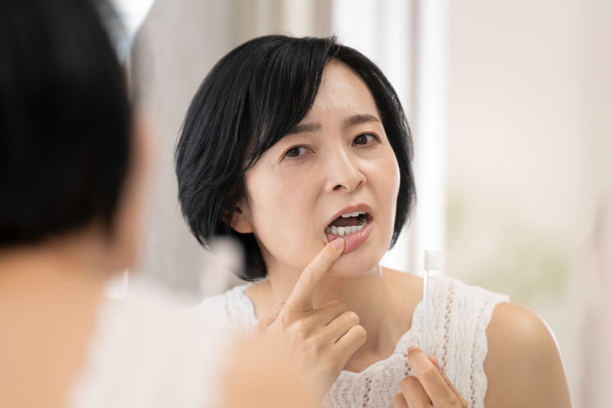 歯周病を鏡で確認するミドル女性