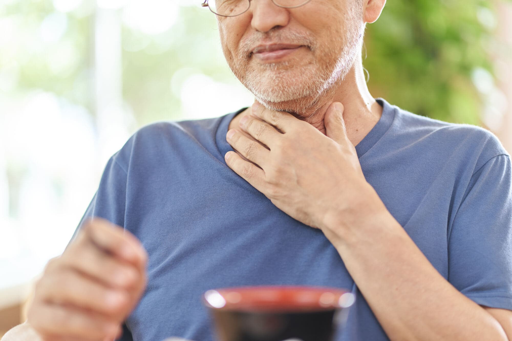 喉をおさえる高齢男性