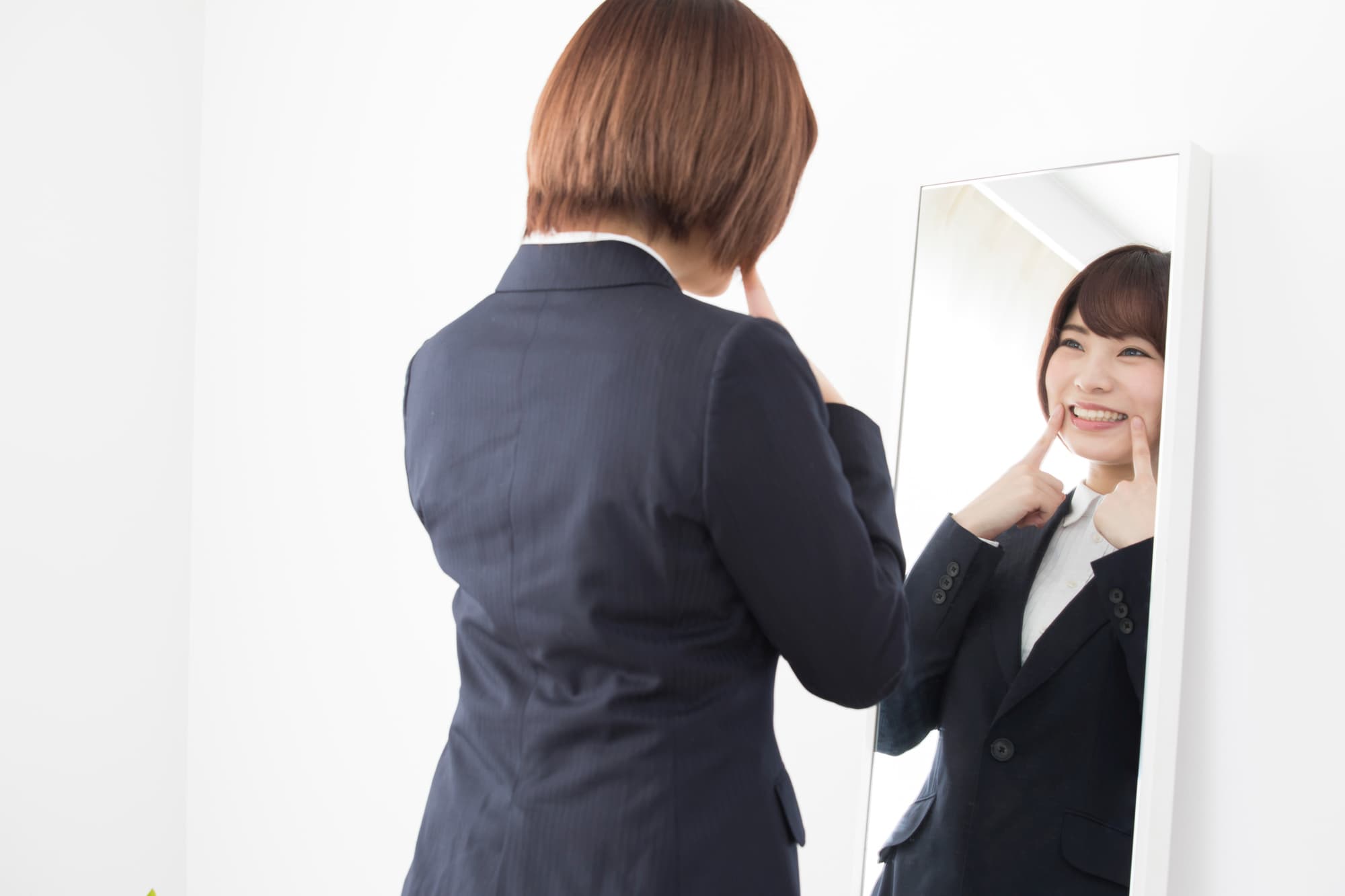 鏡の前で笑う練習をする女性